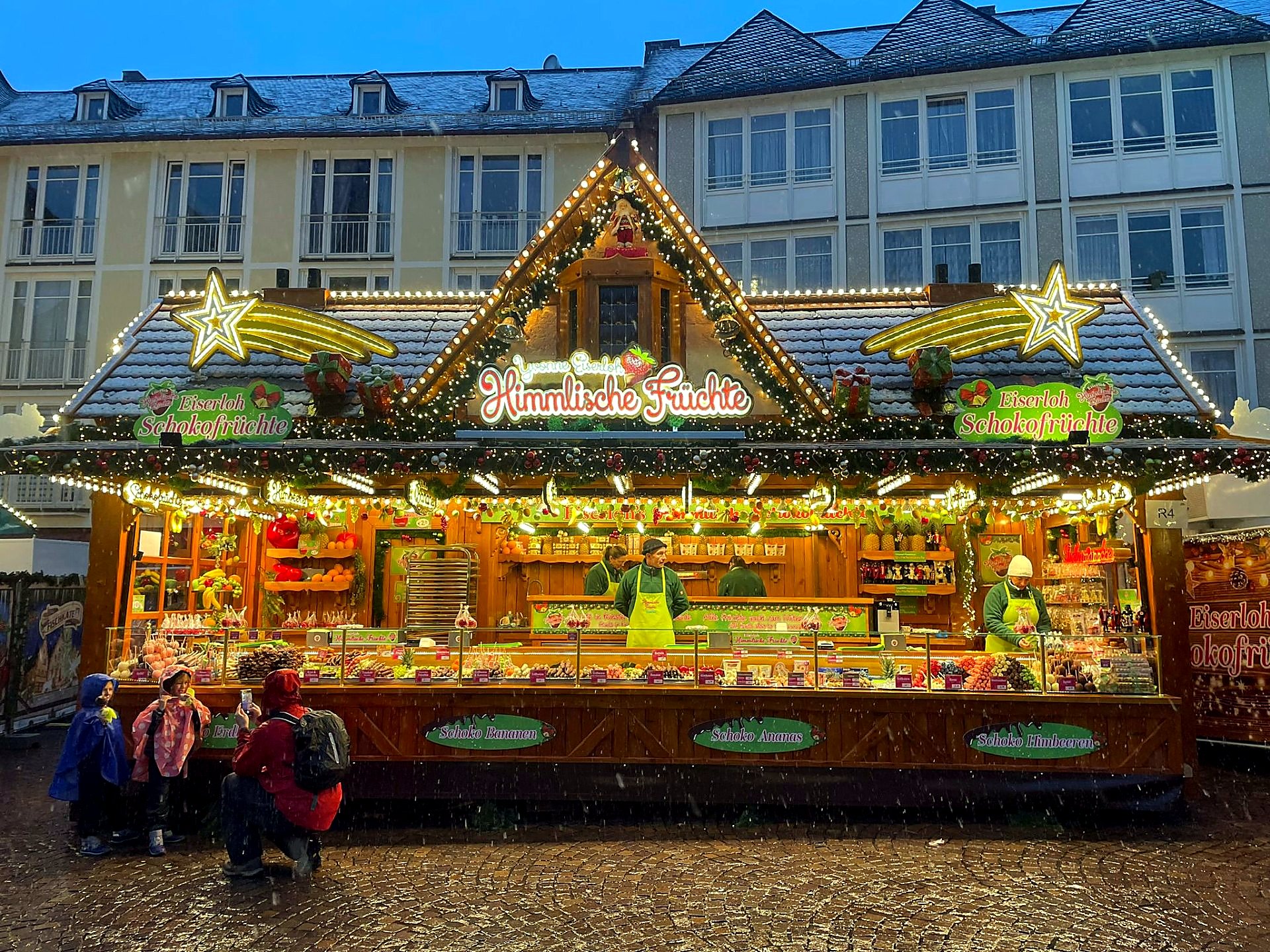 Schokofrüchte-Stand am Römerberg bei Schneefall mit Familie davor